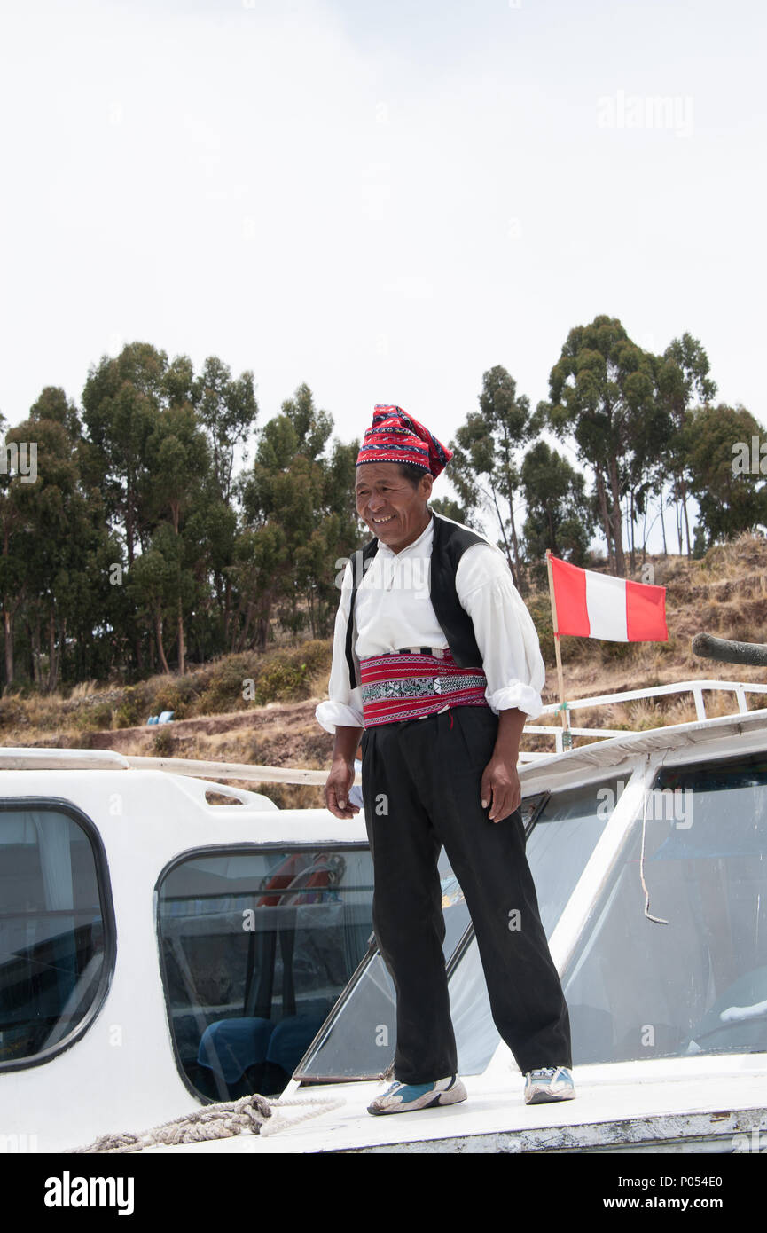 Un propriétaire de bateau local se tient sur son bateau dans l'île de Taquile, le lac Titicaca. Pérou Banque D'Images