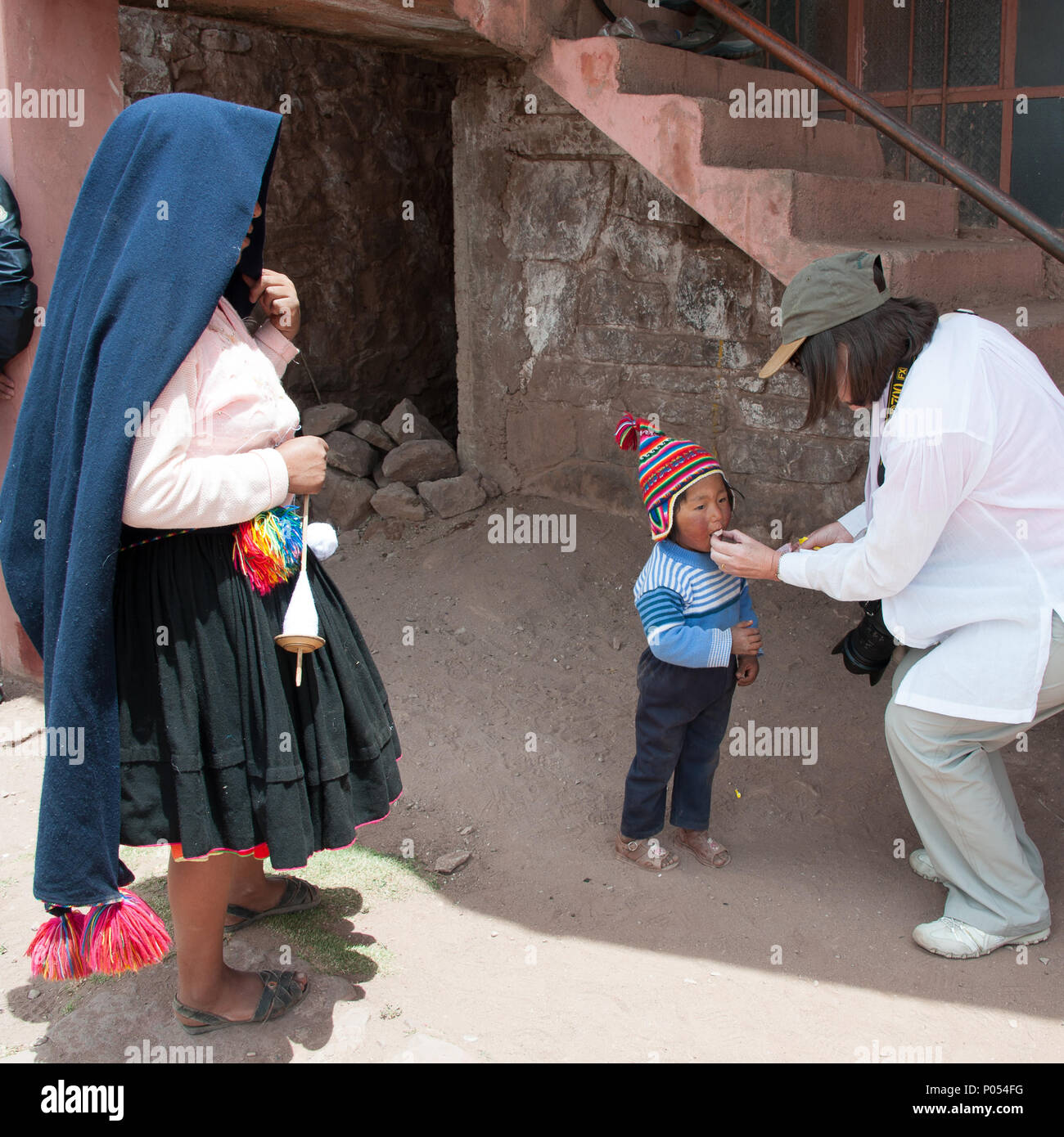 Mère et son enfant prend candy sweets à partir d'un tourisme de l'île de Taquile, le lac Titicaca. Pérou Banque D'Images