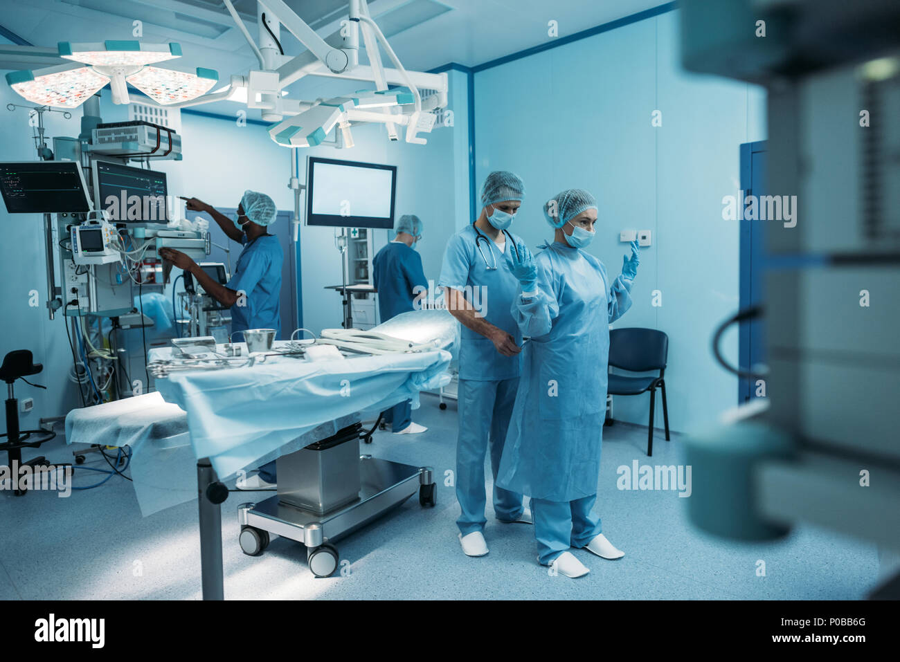 Médecin aidant à porter un uniforme en salle d'opération chirurgicale Banque D'Images