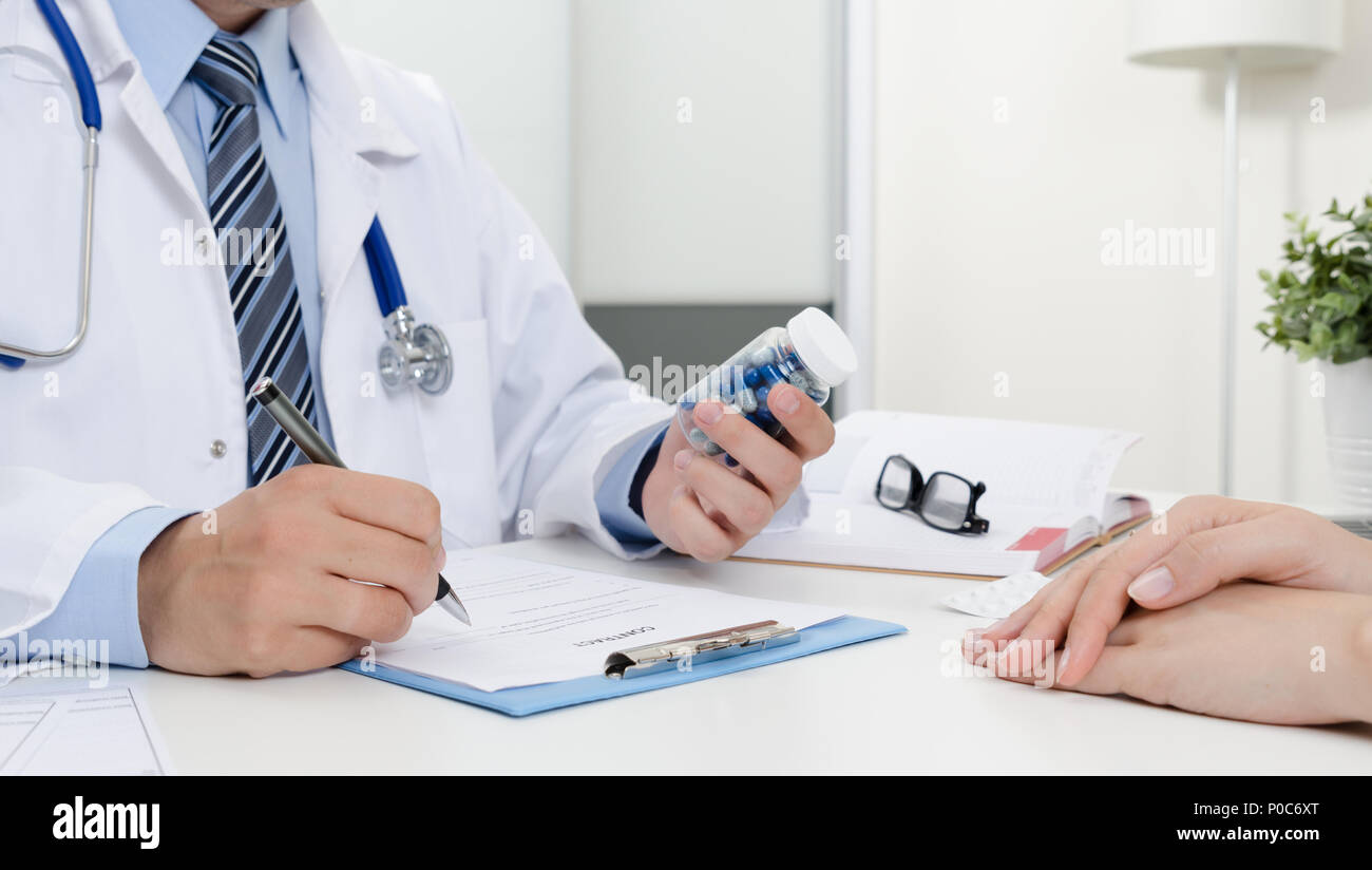 Le médecin et le patient à l'office. Docteur prescrit la recette. Tenant une bouteille de pilules. Banque D'Images