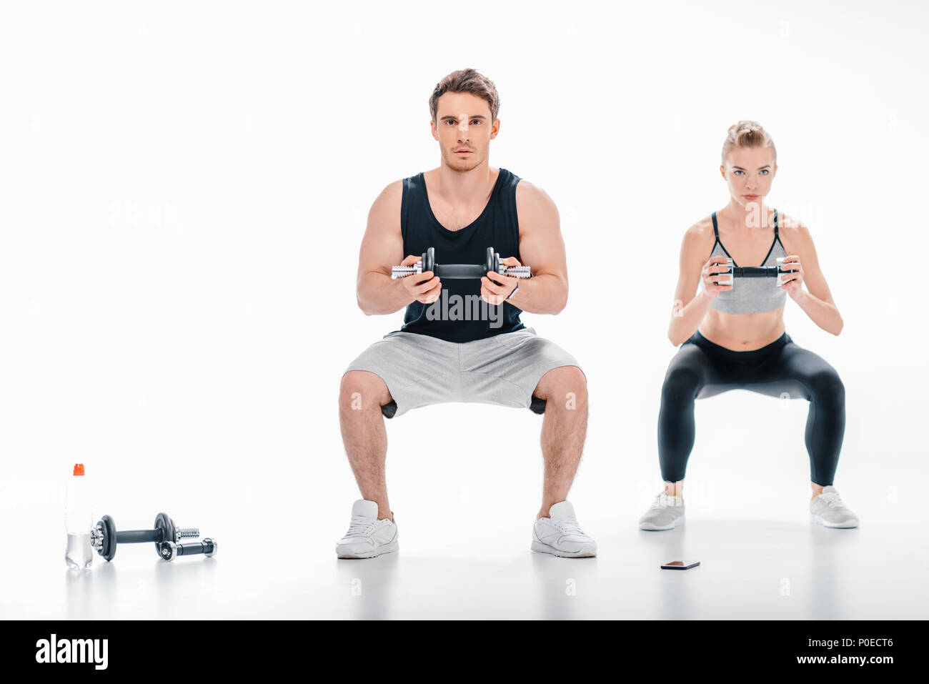 Yougn couple doing squats avec haltères isolated on white Banque D'Images