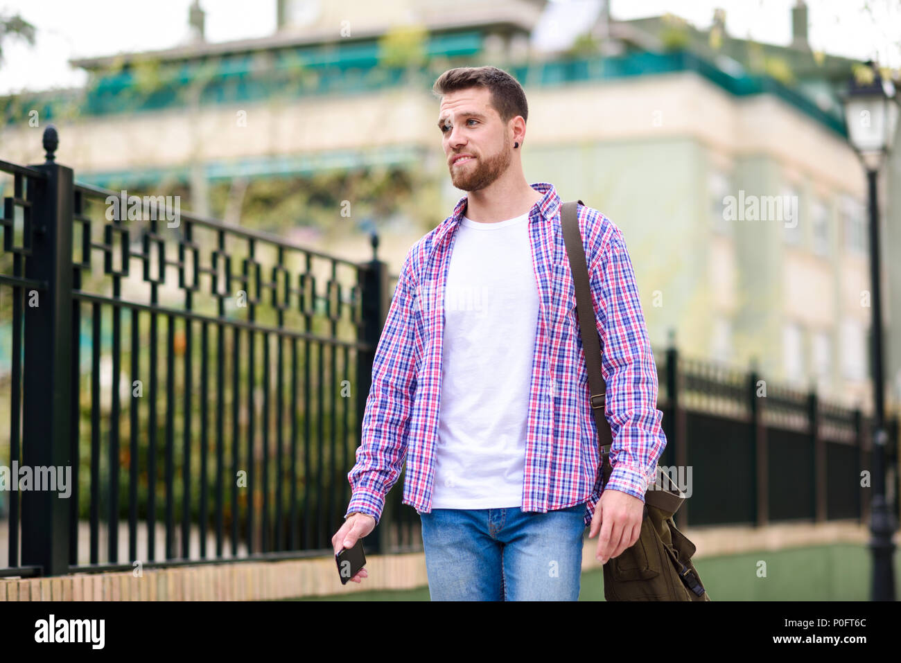 Jeune homme barbu balade en contexte urbain. Porter les tenues de voyageur. Concept de vie. Banque D'Images