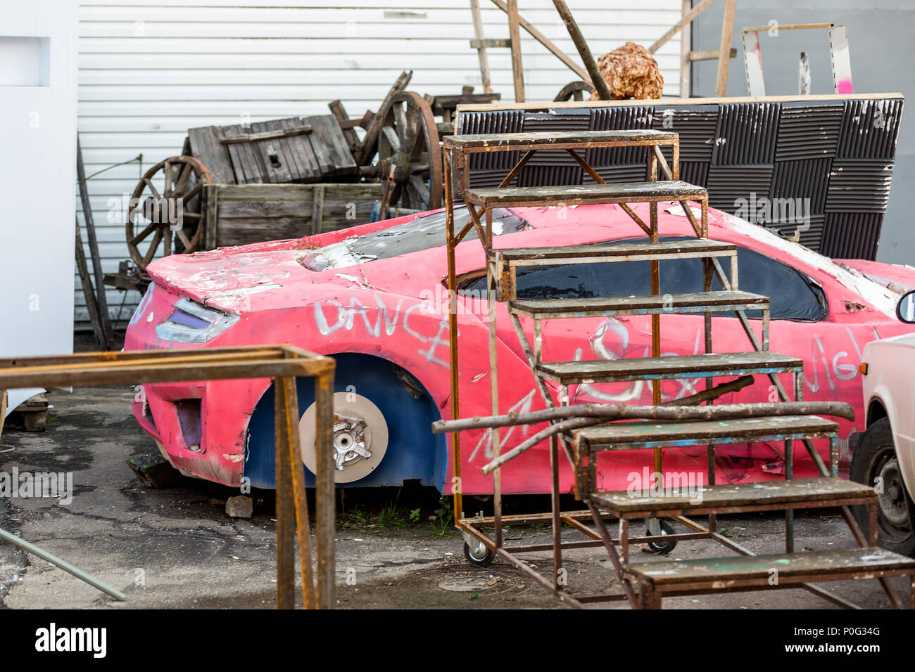 Ancien modèle de minable voiture sport rouge. Structures métalliques rouillées, vieux décor de film paysage sur cour. Banque D'Images