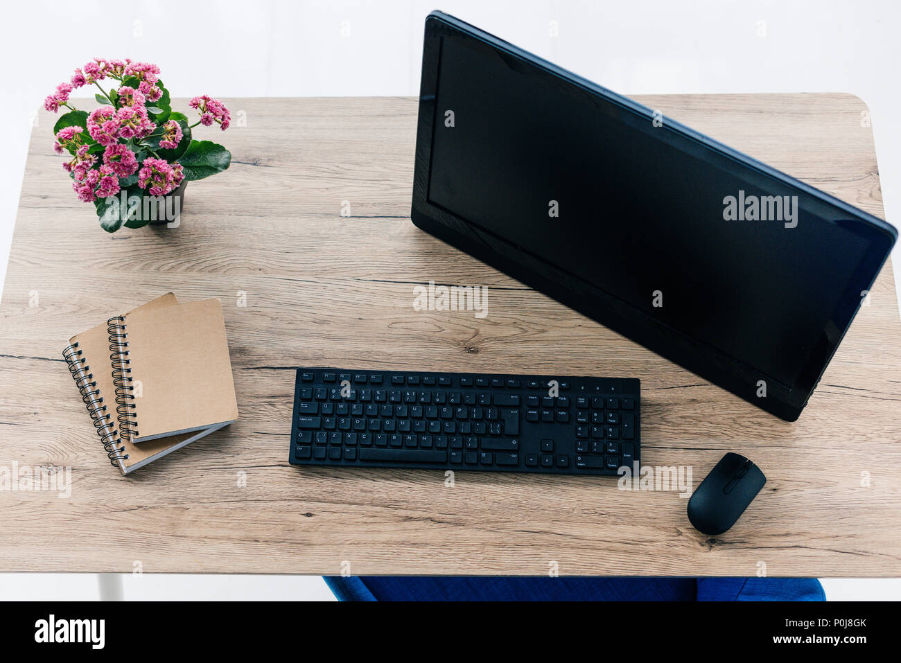 Vue du dessus de l'écran d'ordinateur avec écran vide, des manuels, des fleurs, du clavier et de la souris de l'ordinateur sur la table Banque D'Images