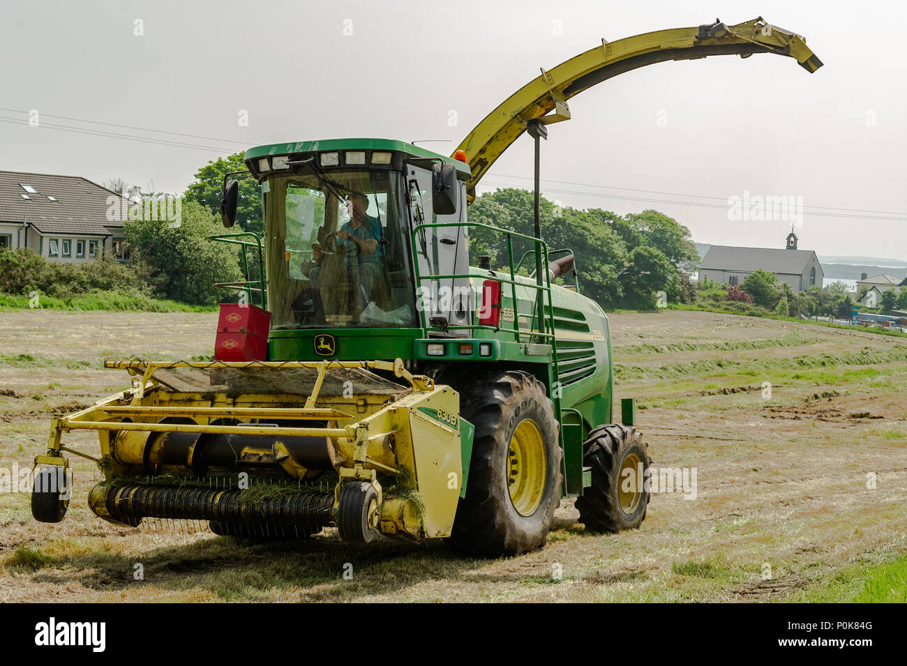 Moissonneuse-batteuse John Deere 7500 au travail la collecte de l'herbe coupée pour l'ensilage dans une ferme à Schull, comté de Cork, Irlande. Banque D'Images