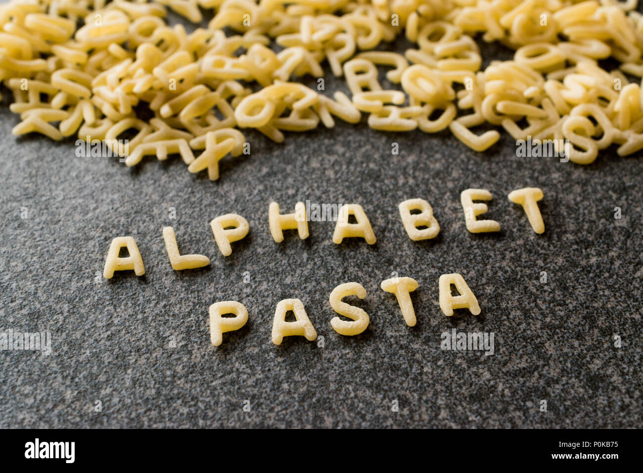 Les pâtes Alphabet brutes est écrit avec des lettres sur la surface gris  granit. Aliments biologiques crus Photo Stock - Alamy