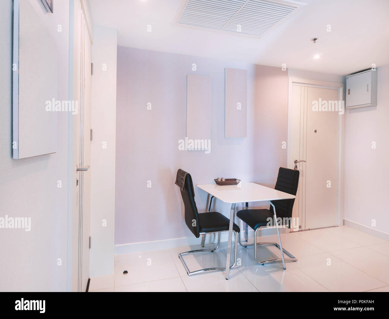 Chambre cuisine moderne blanc décoration mobilier d'intérieur avec table à manger avec une paire de fauteuils en cuir noir avec cadre en acier inoxydable Banque D'Images