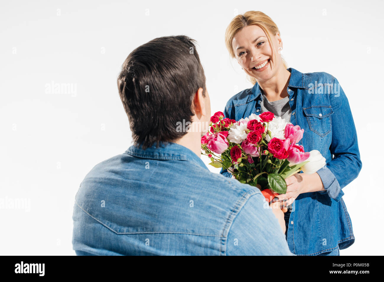 Homme romantique donnant sa petite amie un bouquet de fleurs isolated on white Banque D'Images