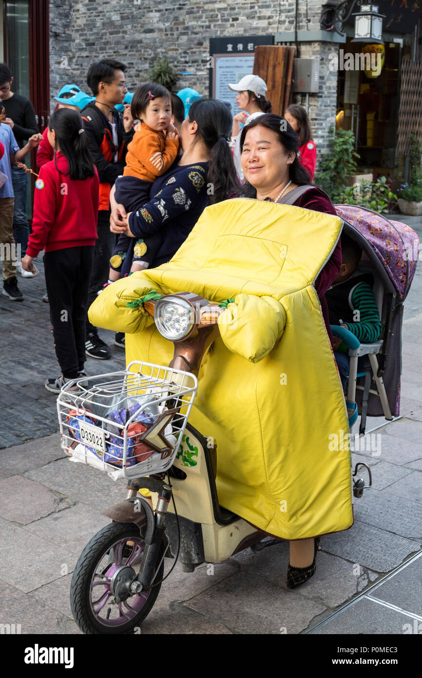 Yangzhou, Jiangsu, Chine. Femme d'âge moyen sur sa moto électrique. Banque D'Images