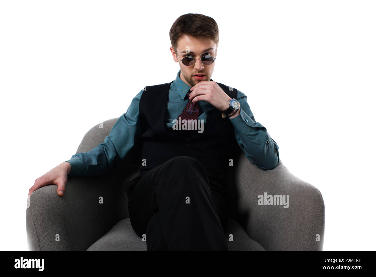 Portrait d'élégante pensive dans spy sunglasses sitting in armchair isolated on white Banque D'Images