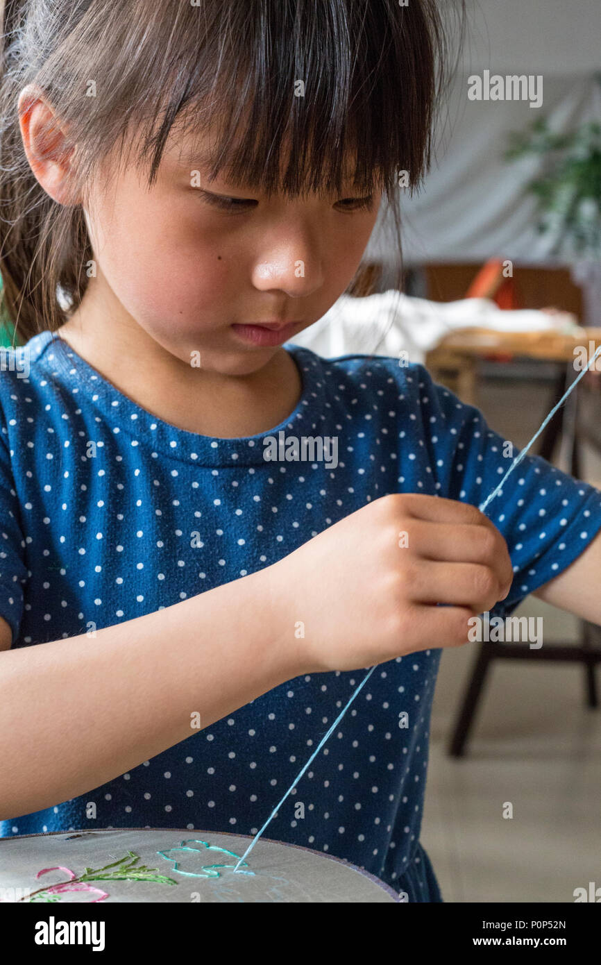 Suzhou, Jiangsu, Chine. Petite fille pratiquant la broderie. Banque D'Images