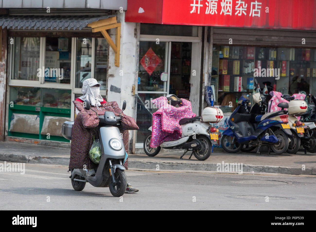 Suzhou, Jiangsu, Chine. Femme avec masque respiratoire, équitation, Moto électrique. Banque D'Images