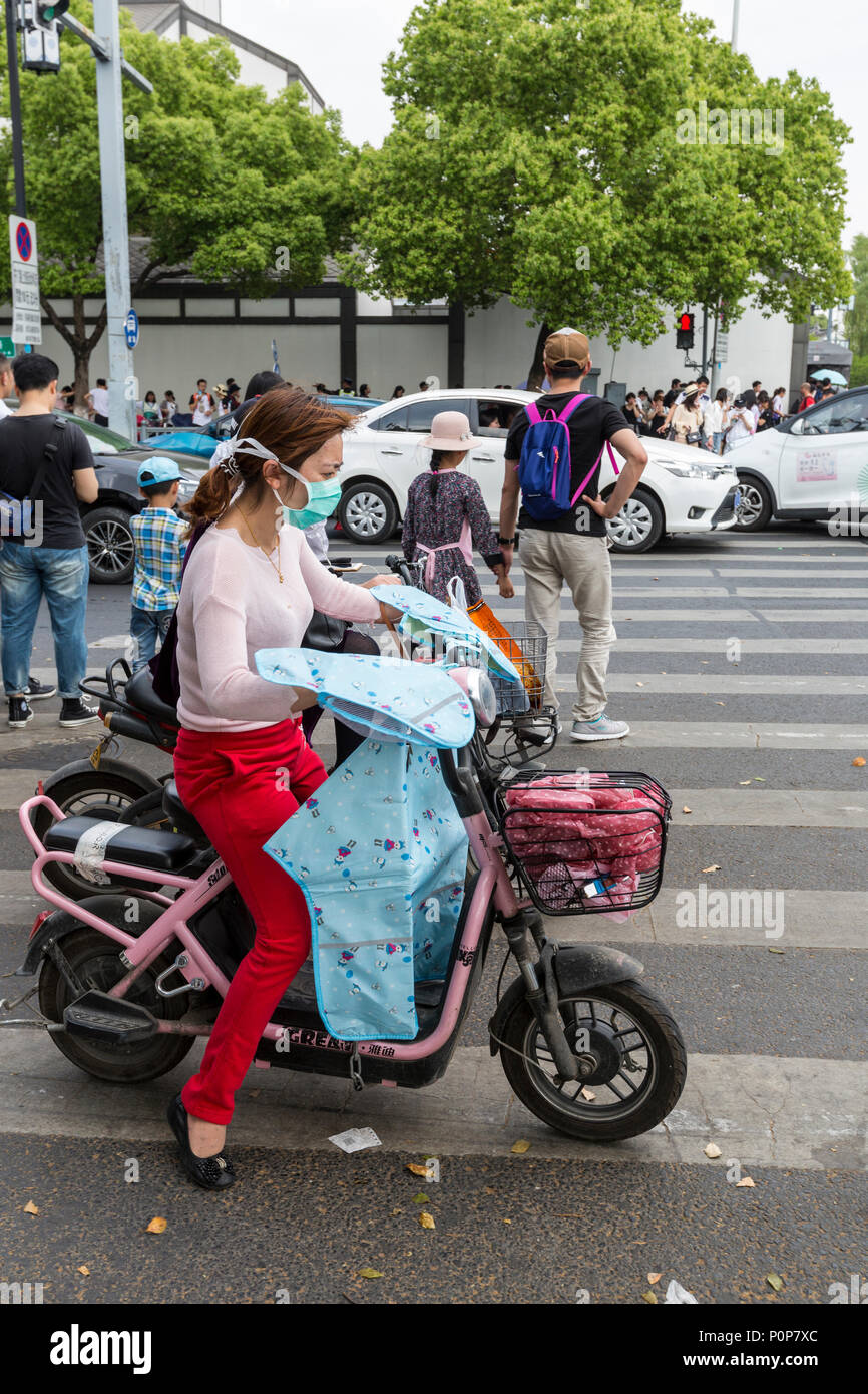 Suzhou, Jiangsu, Chine. Jeune femme en moto avec masque de protection des voies respiratoires. Banque D'Images