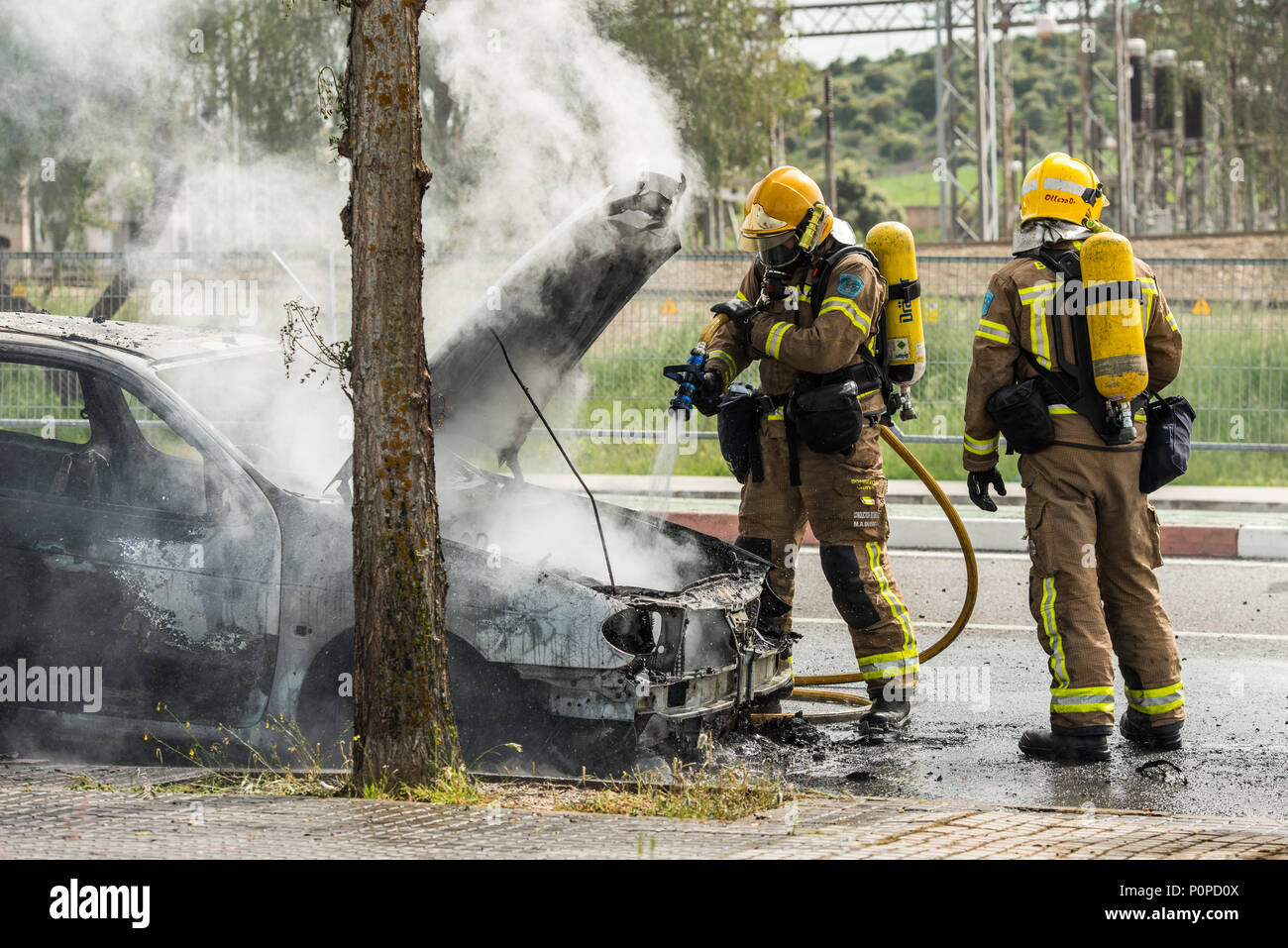 Les pompiers éteindre une voiture qui a brûlé dans une rue de Barcelone. Banque D'Images