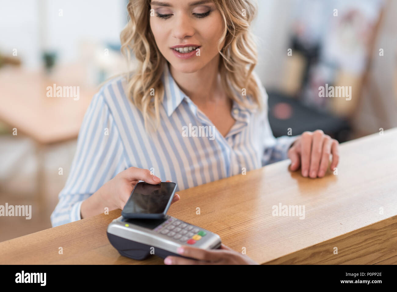 Portrait of beautiful smiling woman using smartphone pour paiement en cafe Banque D'Images