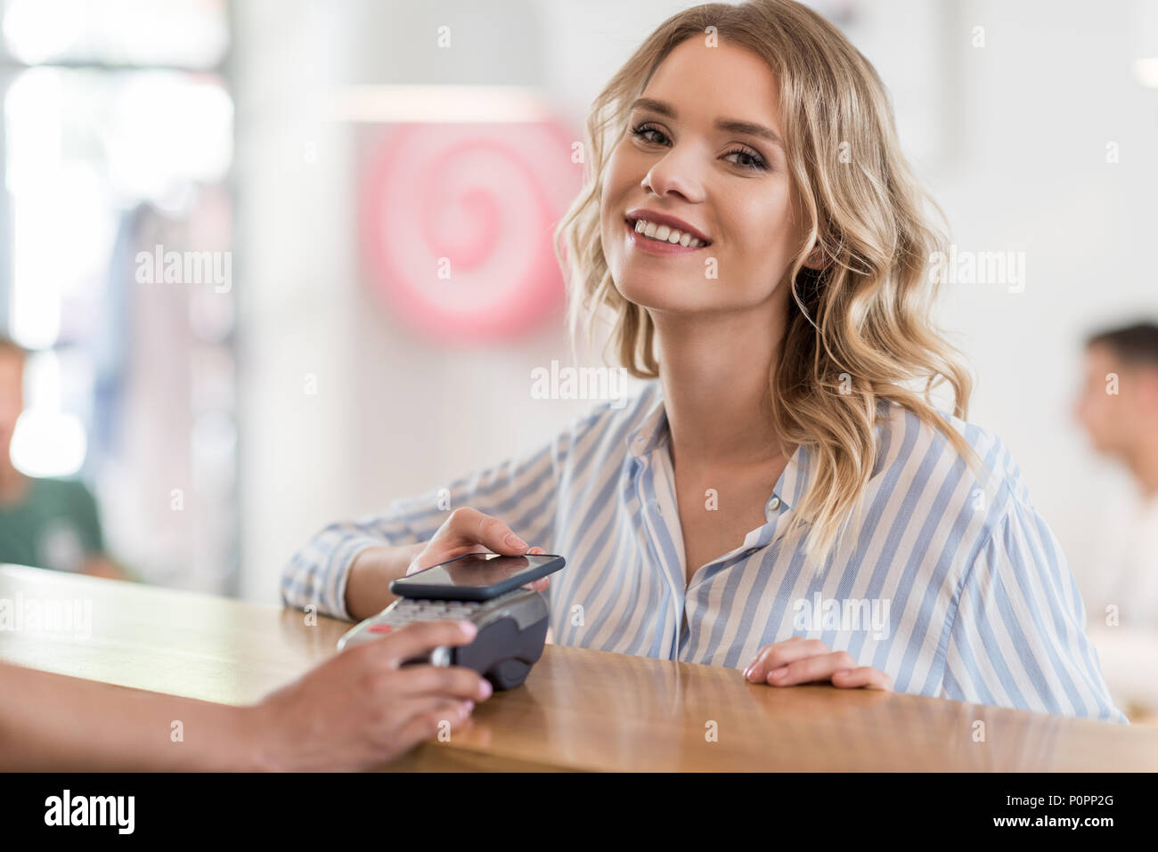 Portrait of beautiful smiling woman using smartphone pour paiement en cafe Banque D'Images