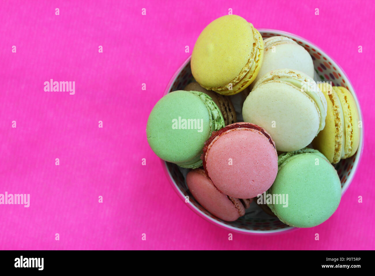 Macarons colorés dans un bol sur vivid pink surface avec copie espace Banque D'Images