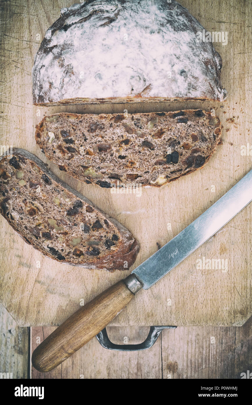 Pain au levain de fruits biologiques avec couteau à pain sur une planche de bois. UK. Vintage filtre appliqué Banque D'Images