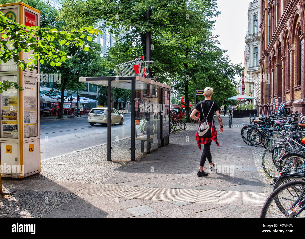 Berlin Mitte Street view. Jeune homme à la mode marche dernières panier abandonné sur le dessus de l'abri de tram Banque D'Images