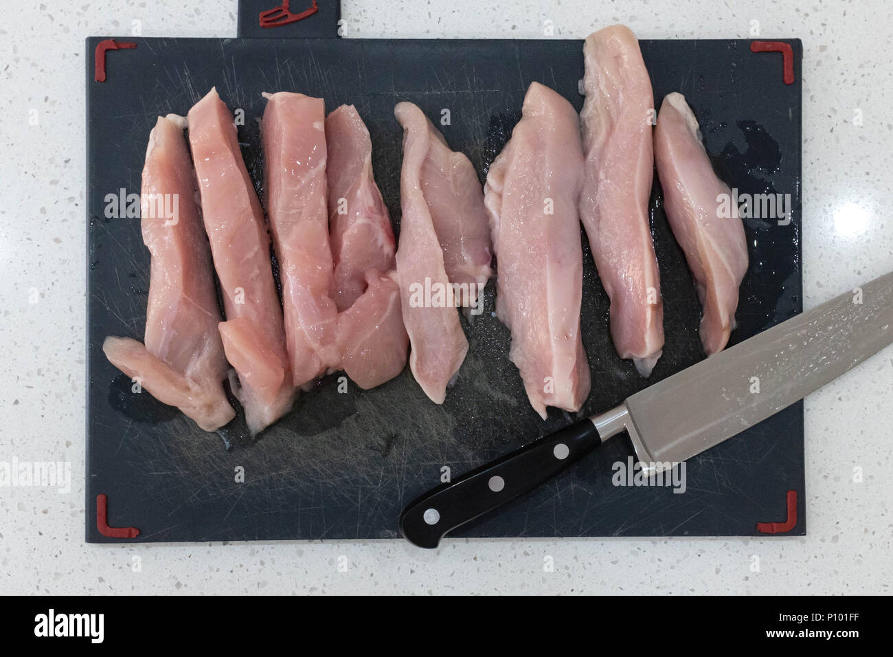 Le poulet cru sur une planche à découper Banque D'Images