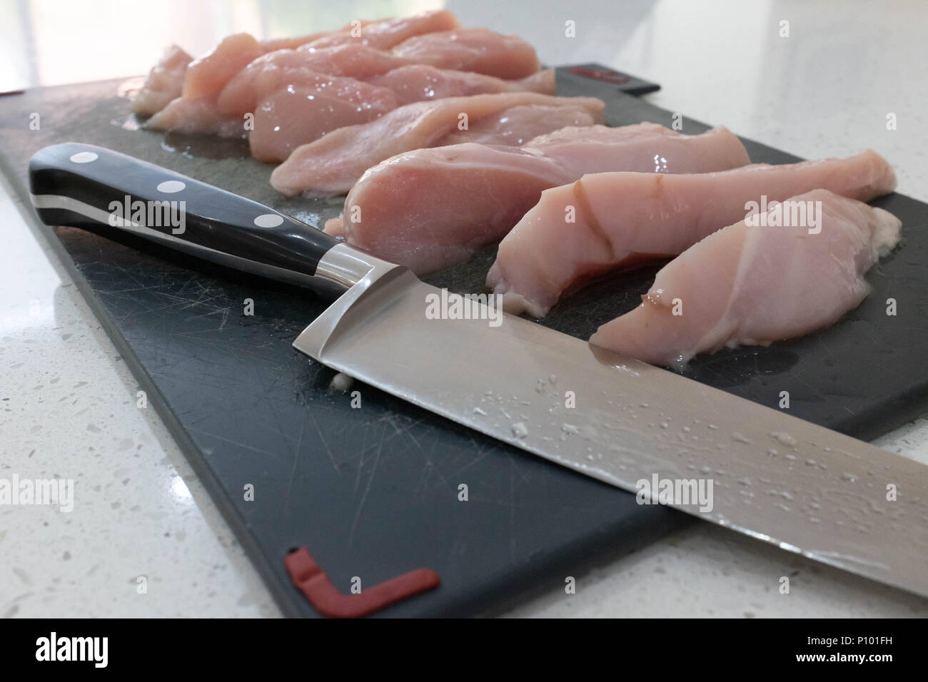 Le poulet cru sur une planche à découper Banque D'Images