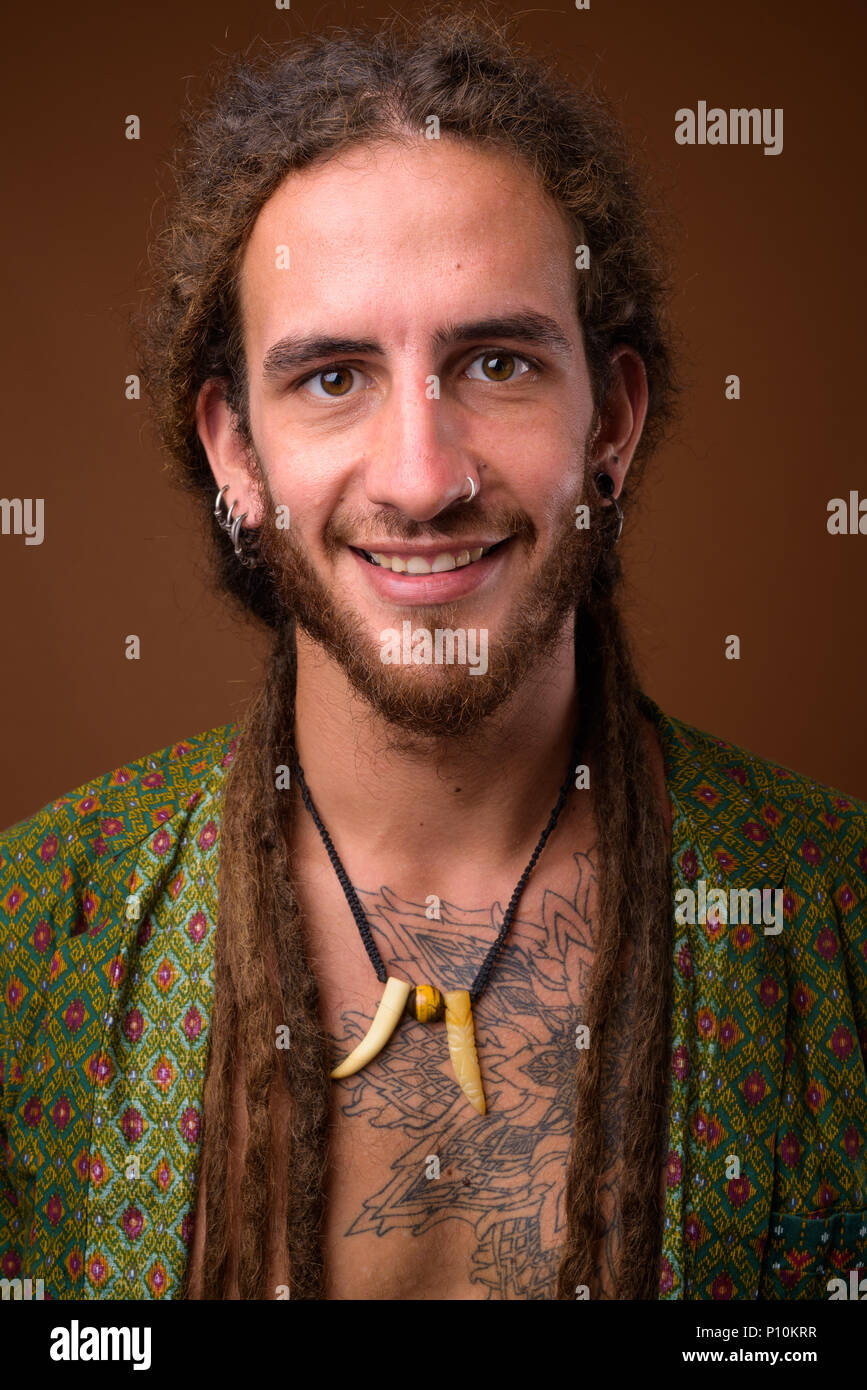 Beau jeune homme hispanique avec des dreadlocks contre brown zone Banque D'Images