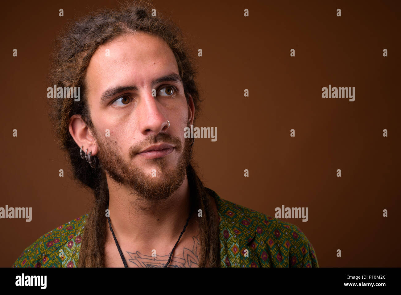 Beau jeune homme hispanique avec des dreadlocks contre brown zone Banque D'Images