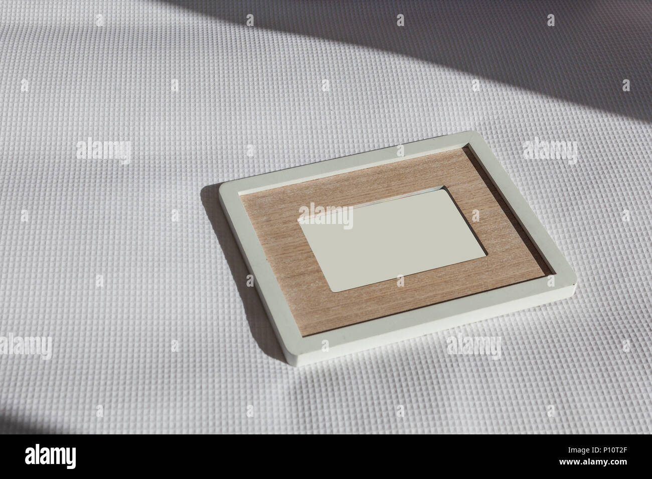 Cadre photo vide avec passepartout allongé sur des draps blancs dans un  rayon de lumière Photo Stock - Alamy