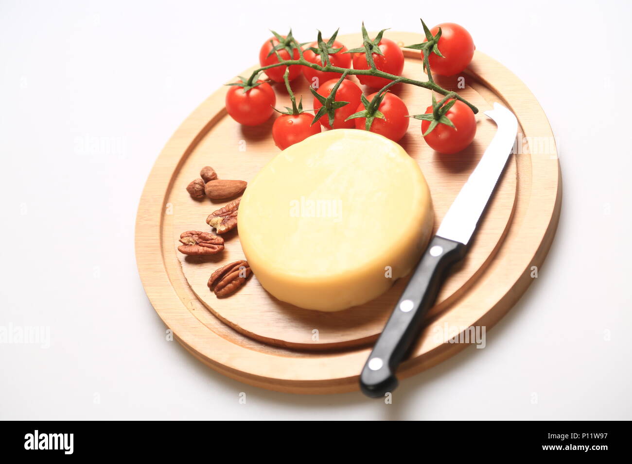 Petite meule de fromage à côté de tomates cerises Banque D'Images