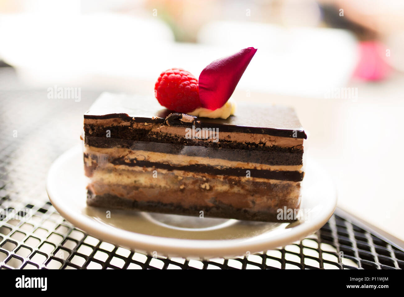 Une tranche de gâteau opéra au chocolat garnie de fraises sur une plaque blanche, sur une table en métal à la terrasse d'un café à la Nouvelle Orléans, Louisiane. Banque D'Images
