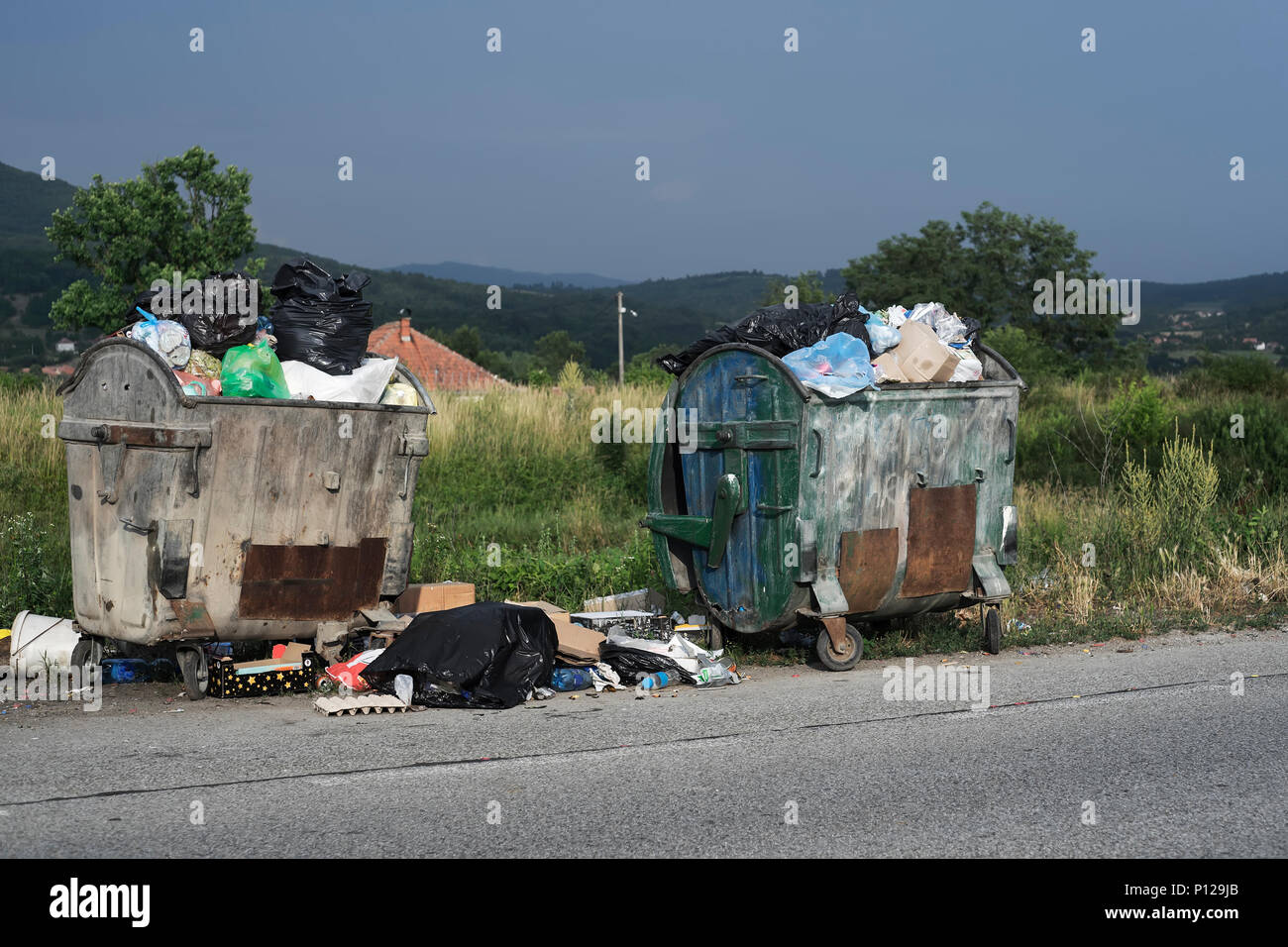 Corbeille remplie et sacs à déchets avec les déchets alimentaires dans la rue Banque D'Images