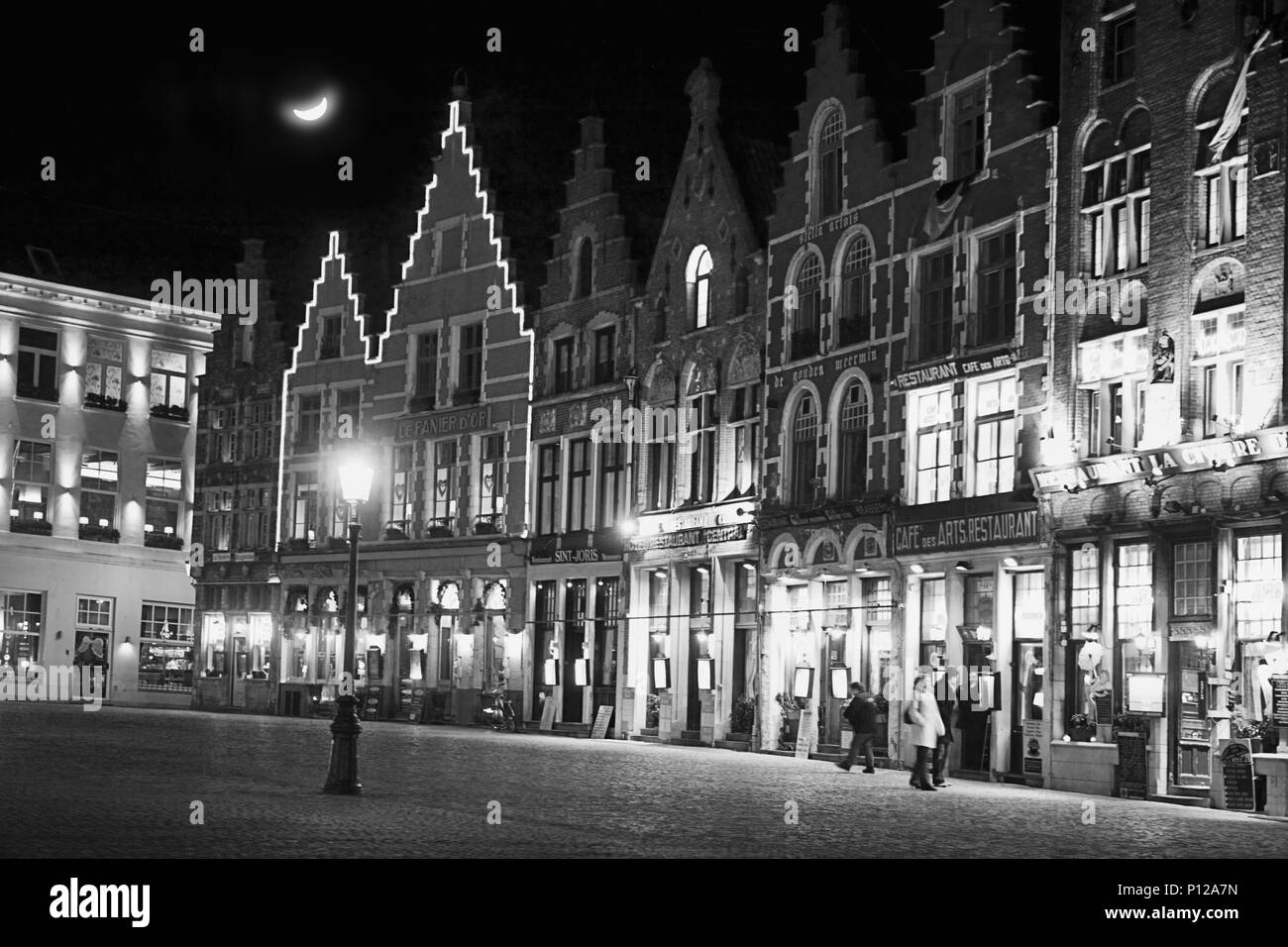 Le côté nord de la Grand Place de nuit, éclairé brillamment avec cafés et bars, Brugge, Belgique : version noir et blanc Banque D'Images