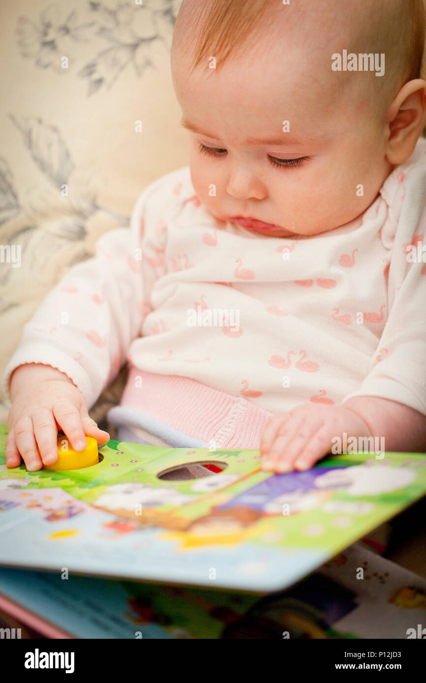 6 mois bébé fille avec un livre Banque D'Images