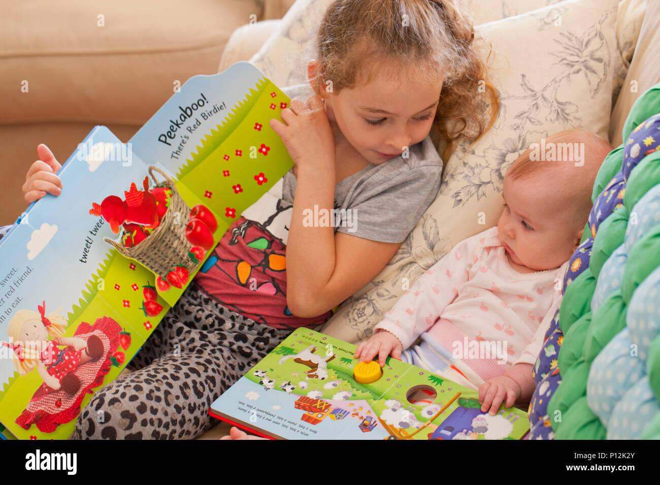 Fillette de six ans a lire à son bébé cousin Banque D'Images