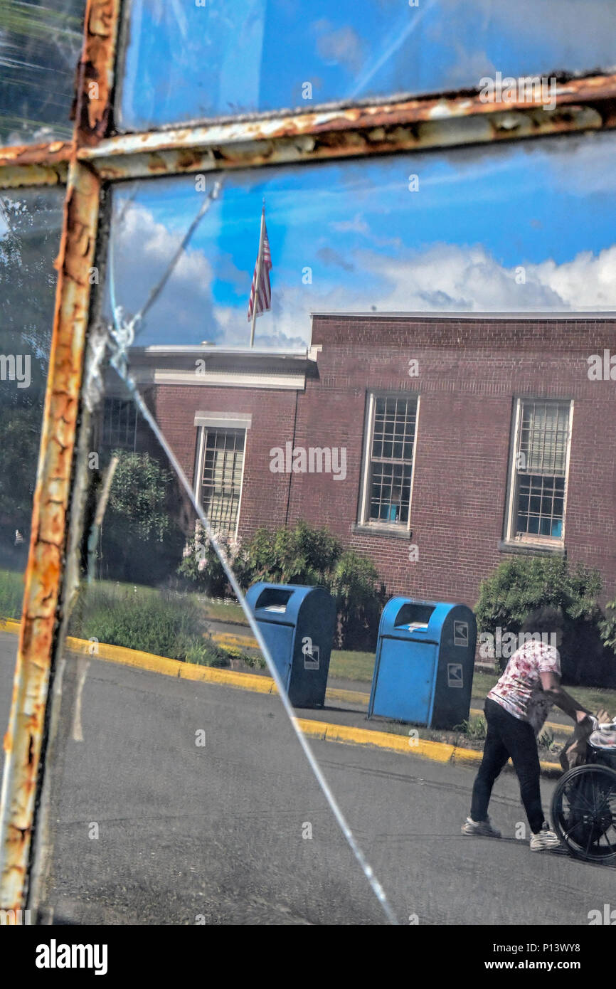 La Gloire, rouillé titre Reflecion photo avec drapeau américain et fenêtre fissuré avec châssis de fenêtre rouillée avec femme poussant un fauteuil roulant Banque D'Images