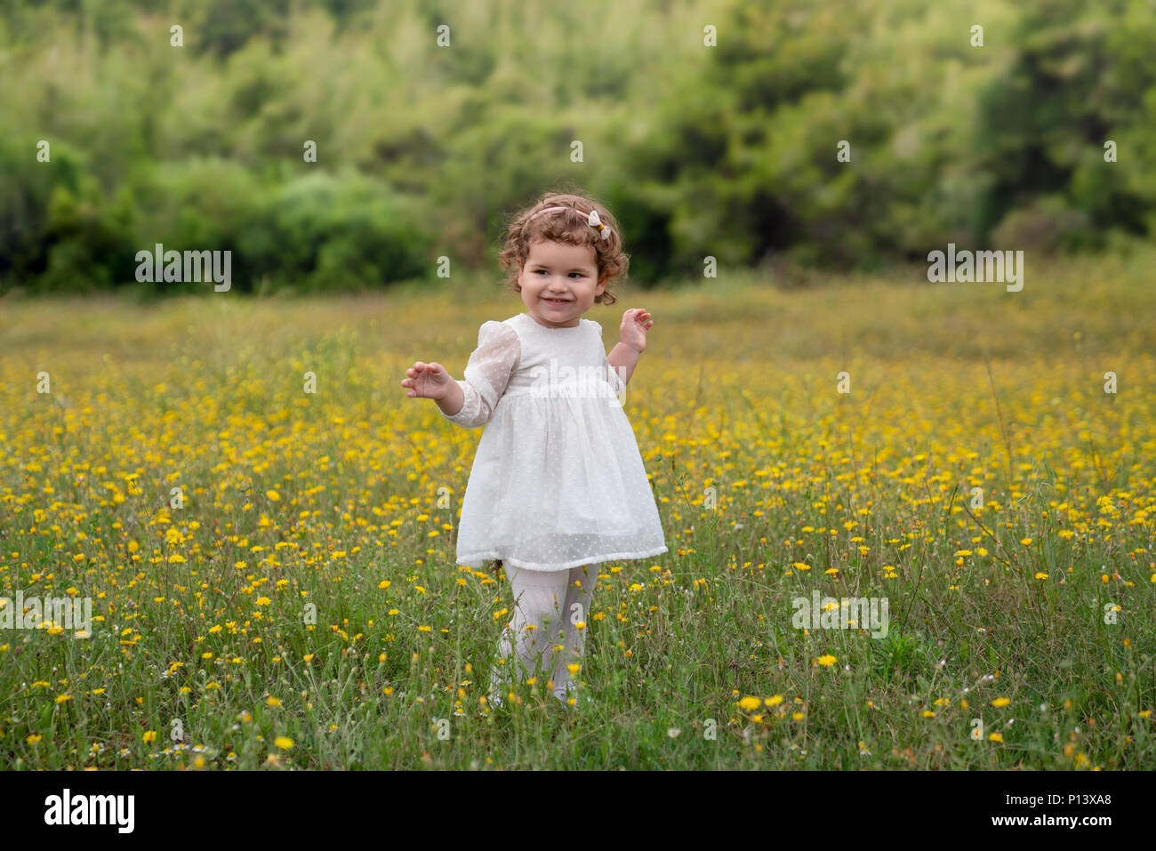 Sweet girl in green meadow avec des fleurs jaunes. Banque D'Images