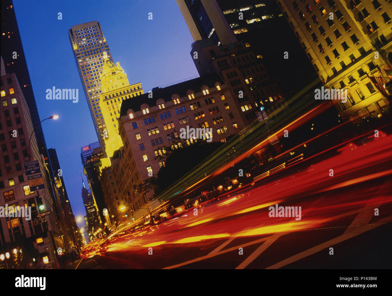 La ville de New York sur la 5ème Avenue, en regardant vers le sud, avec des traces de circulation et les bâtiments illuminés à la tombée de la nuit, New York, NY, USA Banque D'Images