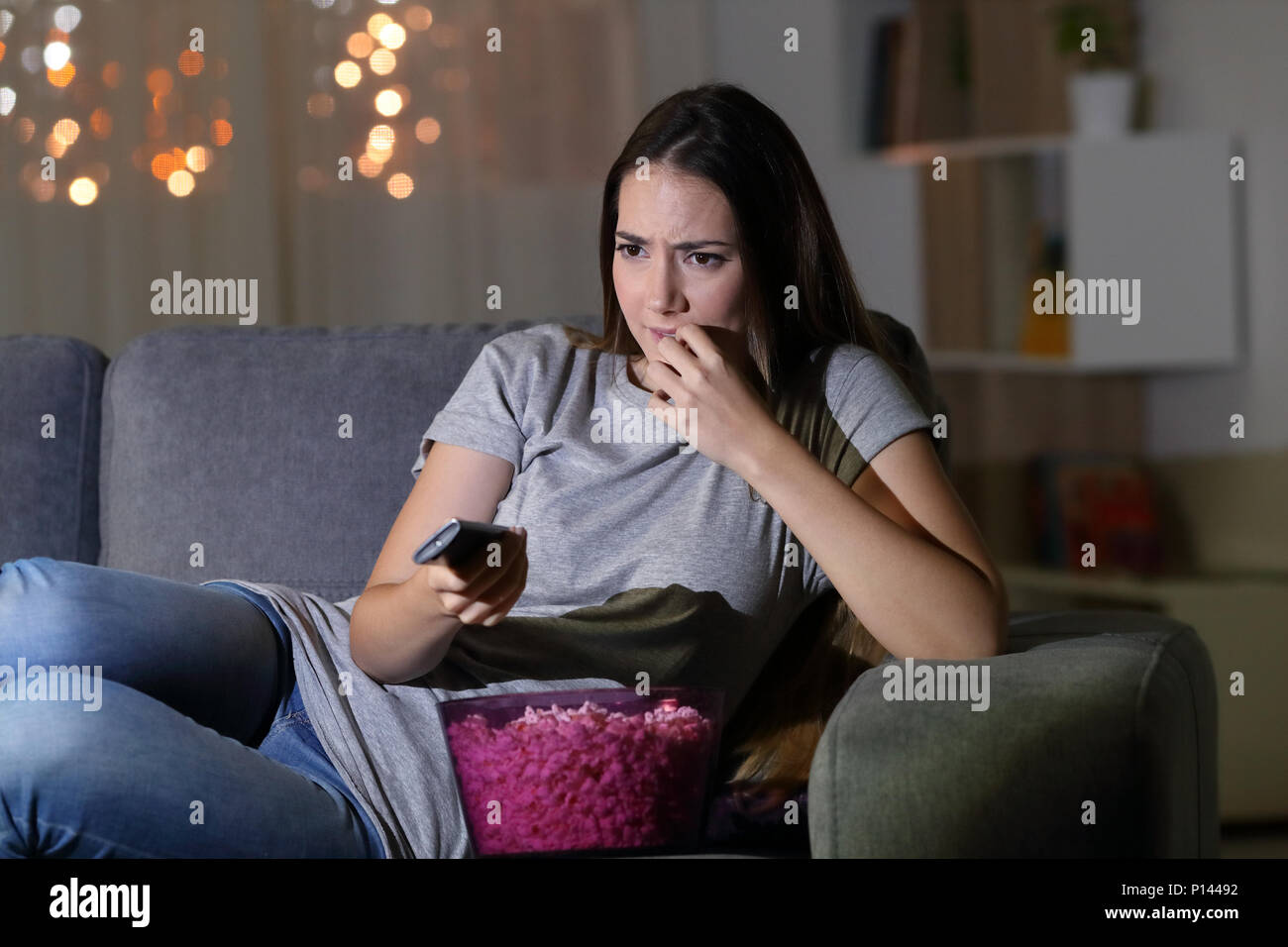 Spectateur nerveux devant la télévision à la maison dans la nuit, assis sur un canapé dans le salon Banque D'Images