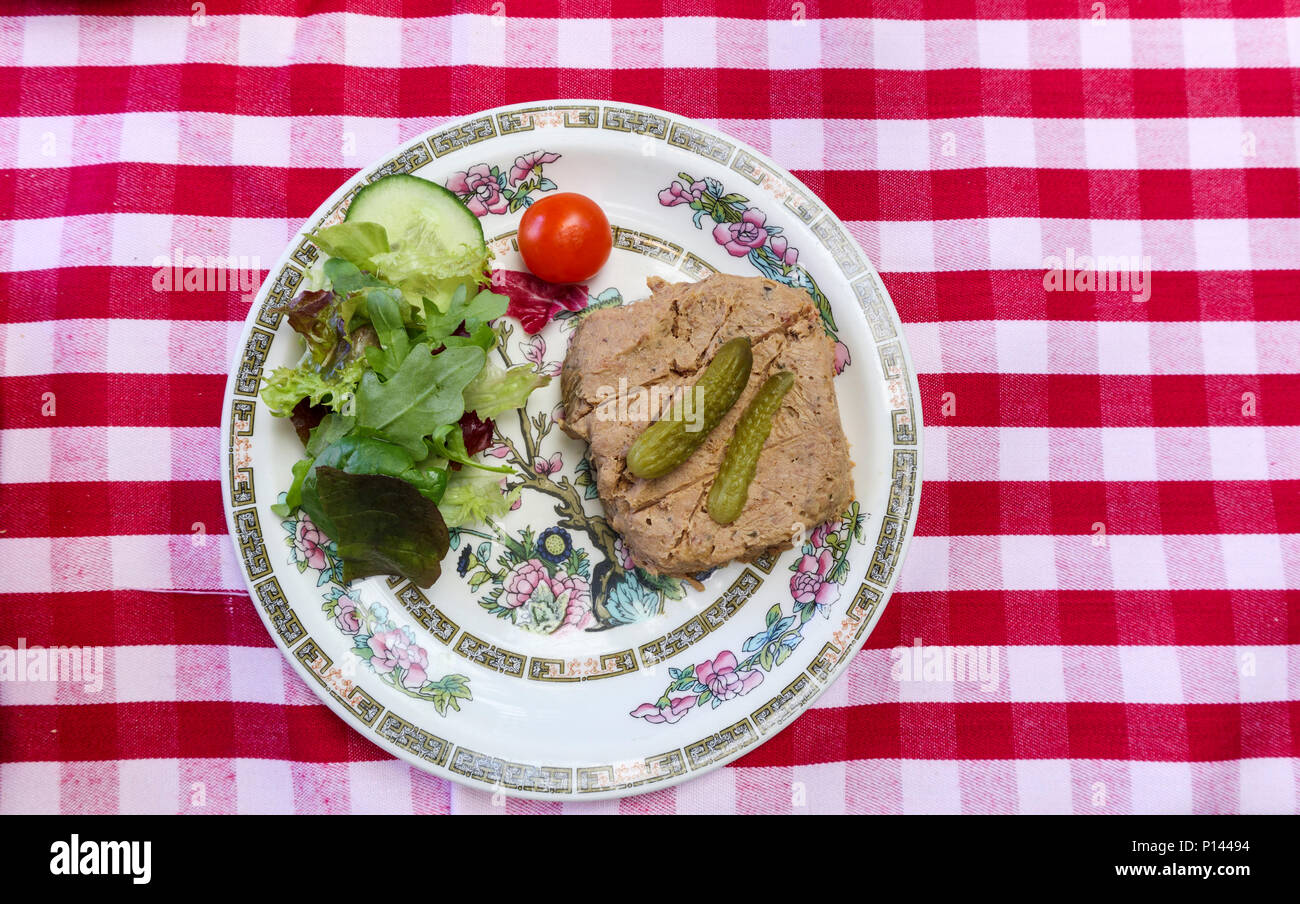 Pub typiquement anglais : une plaque de pate avec salade et cornichons, avec un imprimé vichy rouge et blanc fond nappe vérifié Banque D'Images