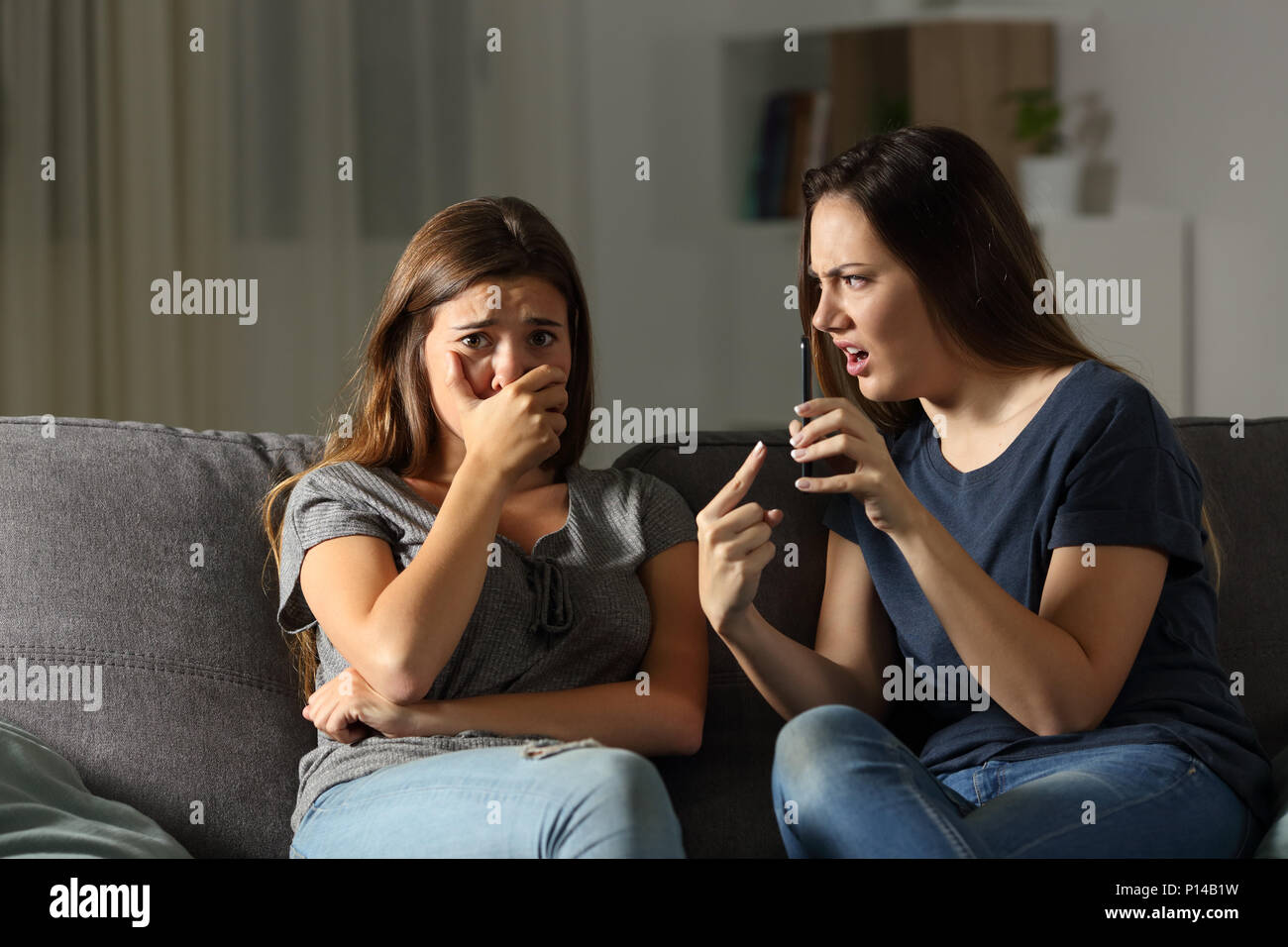 Girl scolding son triste ami de contenus médias assis sur un canapé dans la salle de séjour à la maison Banque D'Images