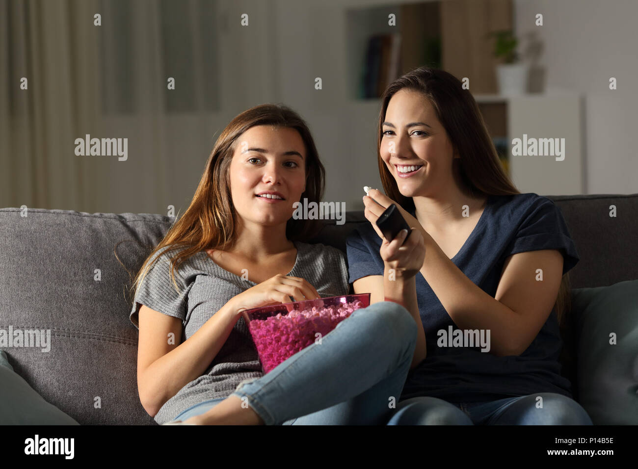 Deux heureux colocataires wathing tv dans la nuit, assis sur un canapé dans la salle de séjour à la maison Banque D'Images