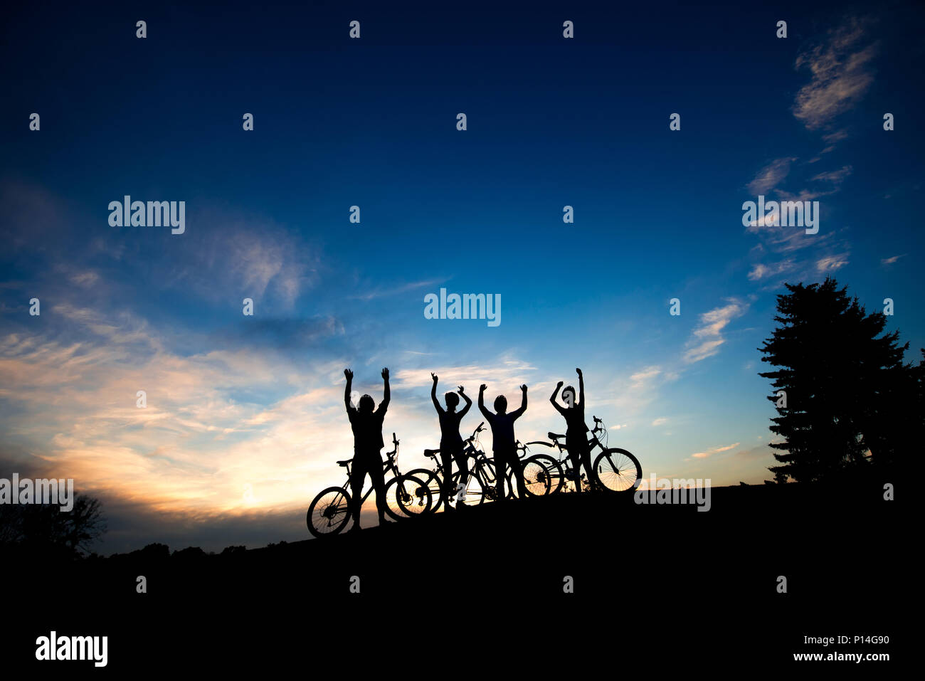 Silhouettes de cyclistes debout sur la colline parlementaire. Quatre amis avec des vélos sur fond de ciel coucher de soleil. Jeune et insouciante. Banque D'Images