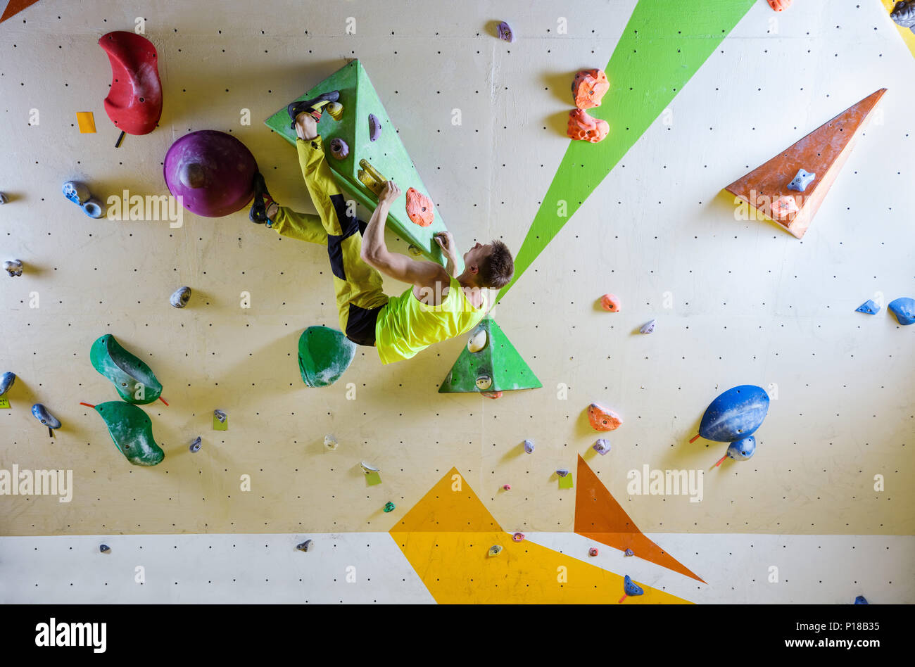 Jeune homme escalade bouldering itinéraire. Dans la salle d'escalade intérieure. Banque D'Images
