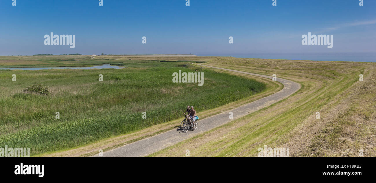Panorama d'un couple à bicyclette le long d'une digue sur l'île de Texel, Hollande Banque D'Images