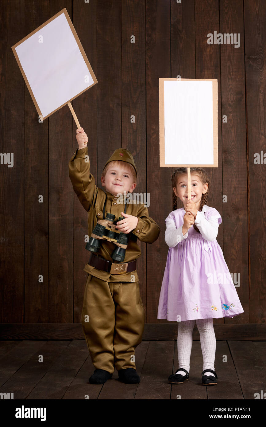 Les enfants garçon sont habillés en soldat en uniforme militaire et rétro  fille en robe rose. Ils êtes holding blank des affiches pour des portraits  d'anciens combattants Photo Stock - Alamy