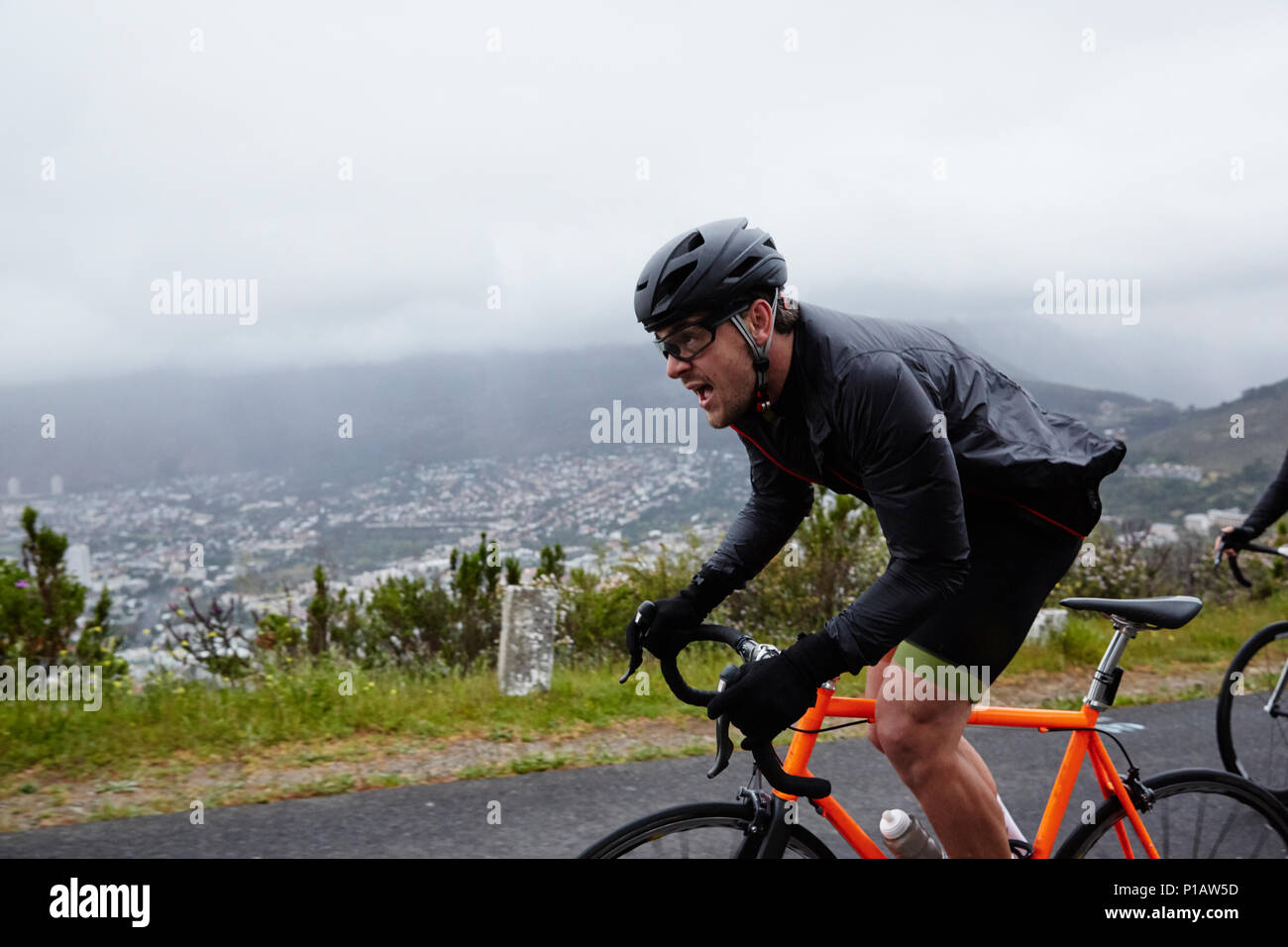 Cycliste homme déterminé à vélo sur route pluvieuse Banque D'Images