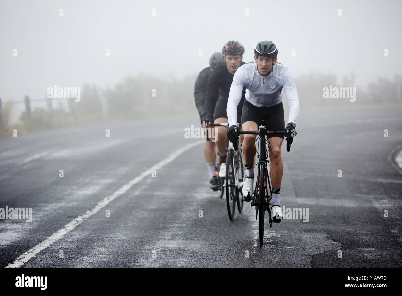 Les cyclistes masculins dédié à vélo sur route pluvieuse Banque D'Images