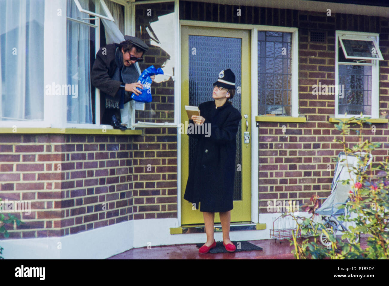 Bizarres et farfelus' 'un homme et une femme s'habiller comme un flic et un voleur tout en posant pour une photo à l'extérieur d'une maison. Mais l'emplacement n'a été prise en 1972. Banque D'Images