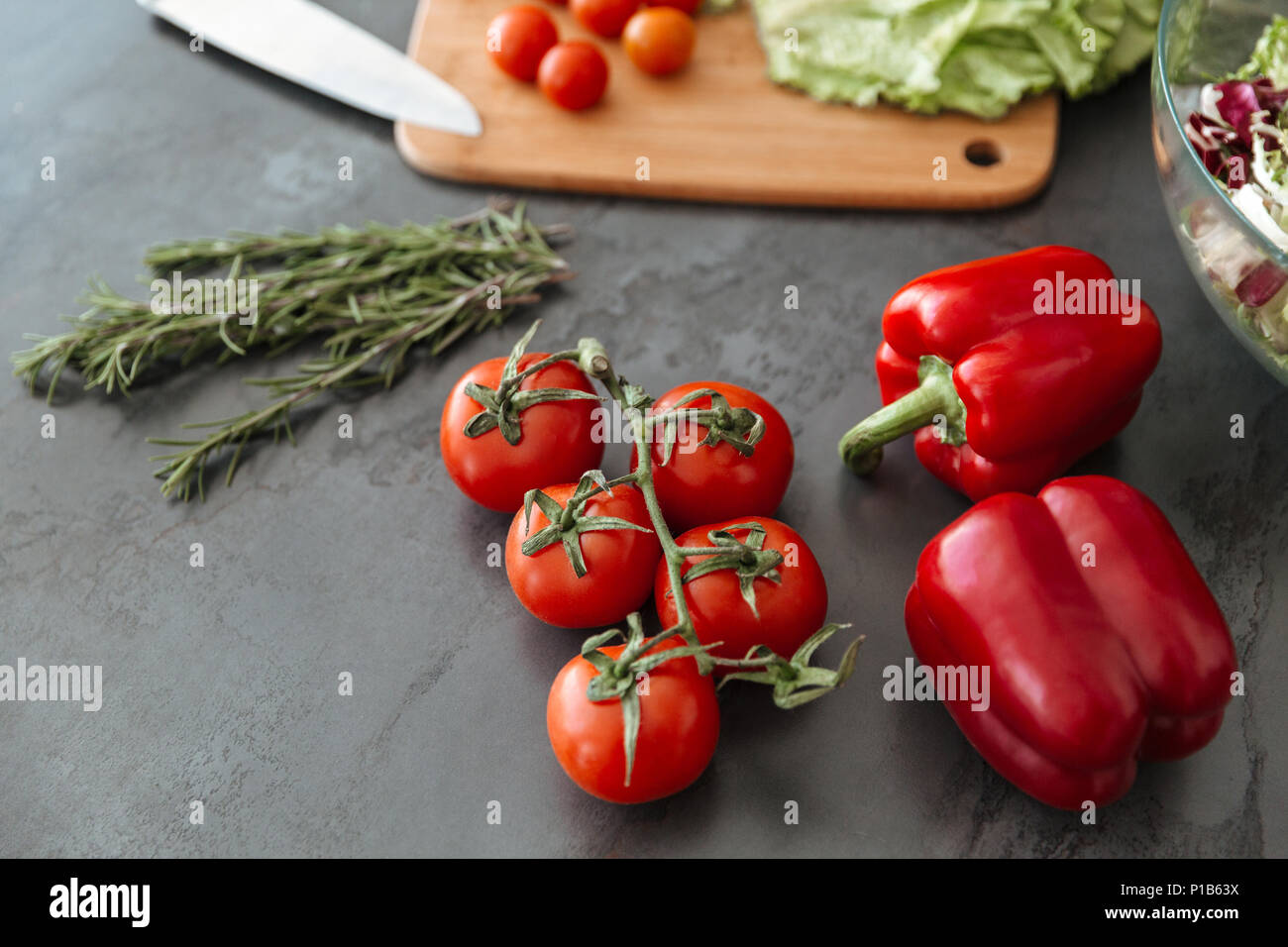 Gros plan d'une table de cuisine avec tomtoes, capsicum et planche à découper Banque D'Images
