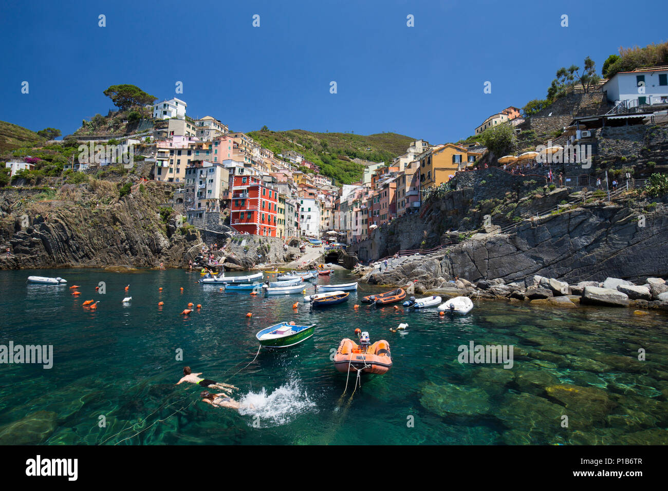 Vue sur village Riomaggiore jeune couple la natation. Cinque Terre, ligurie, italie Banque D'Images